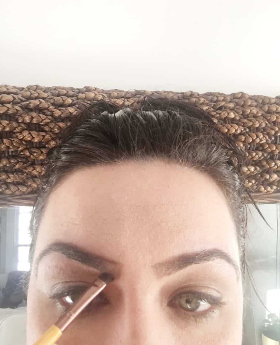 A woman shaping her brows.