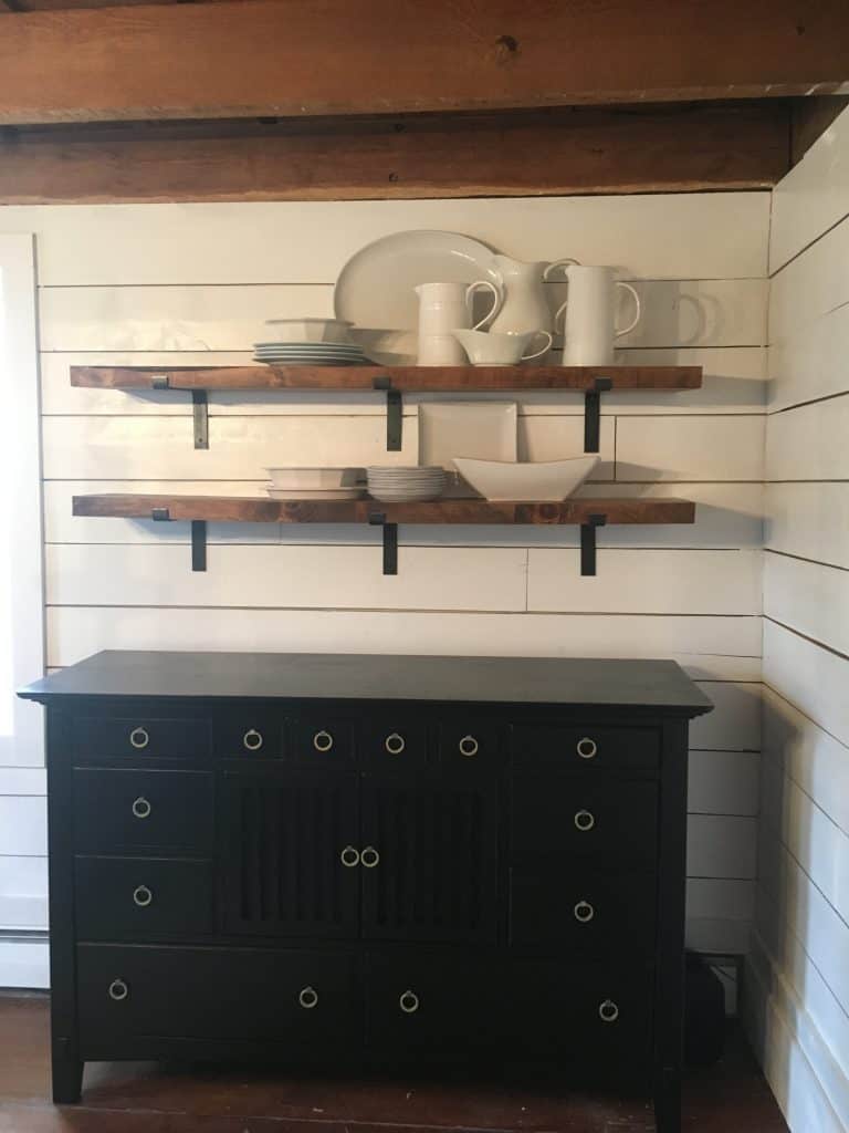 White plates, bowls, and pitcher on the shelves.