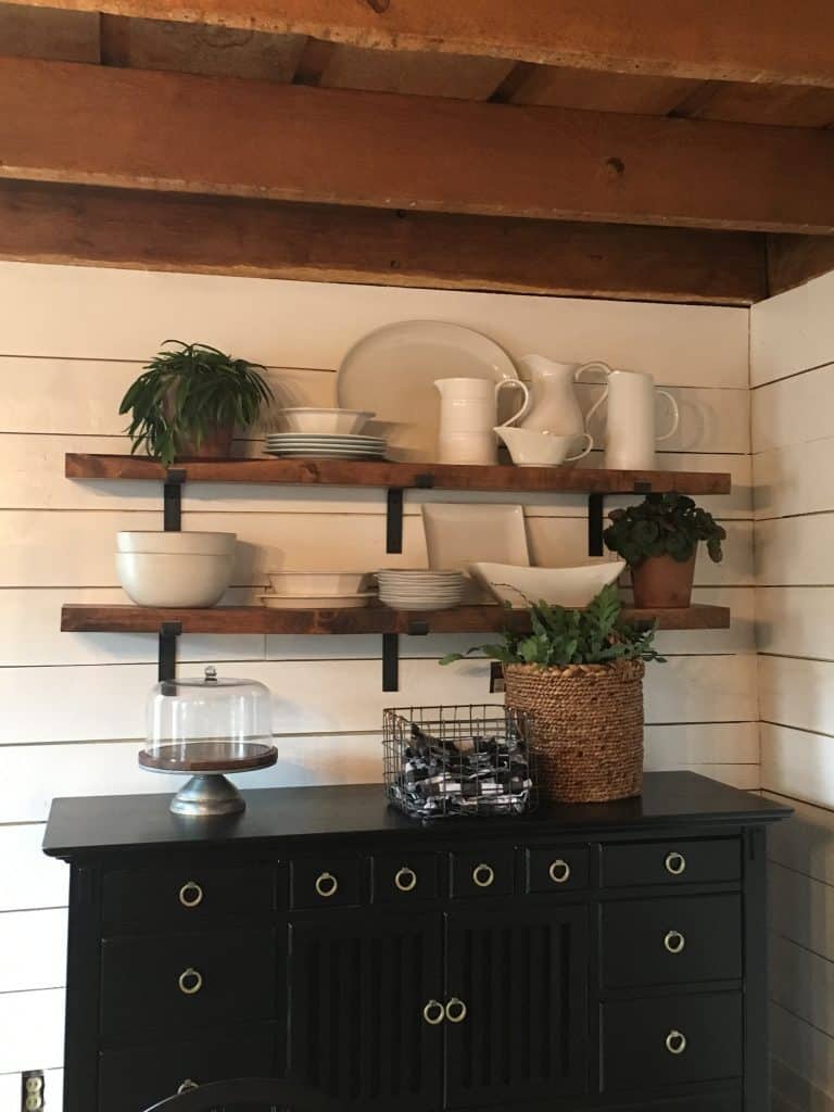 The plant, cake stand and basket on the buffet under the shelves.