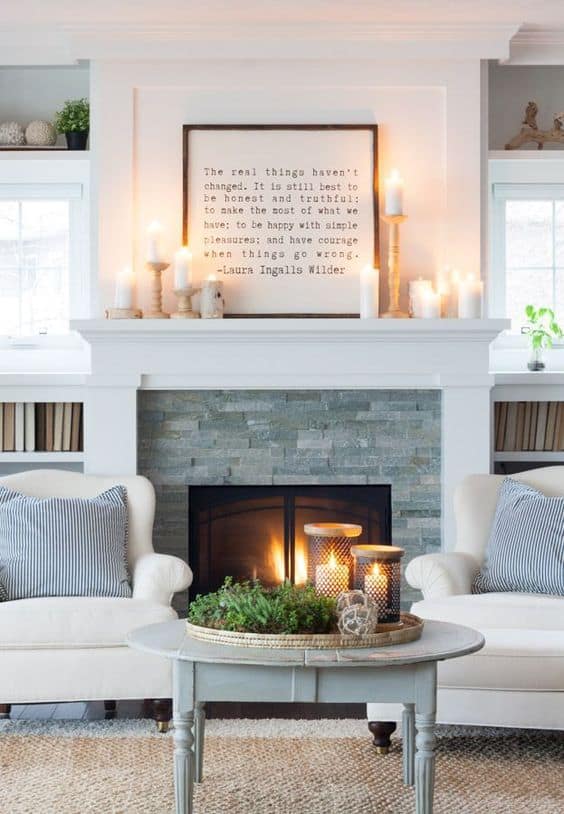 A stone and white mantel with a framed graphic quote on top of the mantel.
