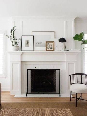 A white minimalist fireplace with pictures on the mantel.