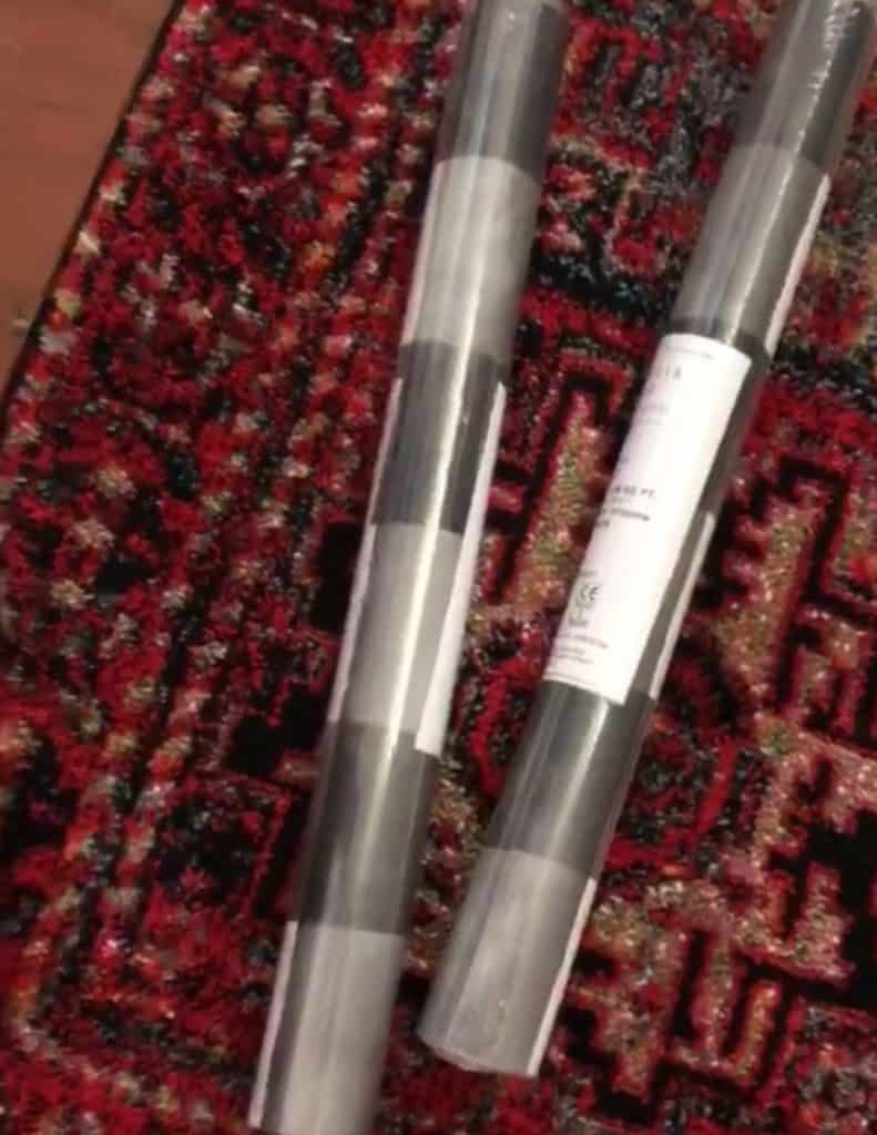 Wallpaper rolls on a rug with red and black tones.