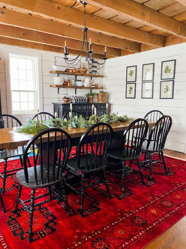 Dining room with real and faux garland on the table with candle sticks.
