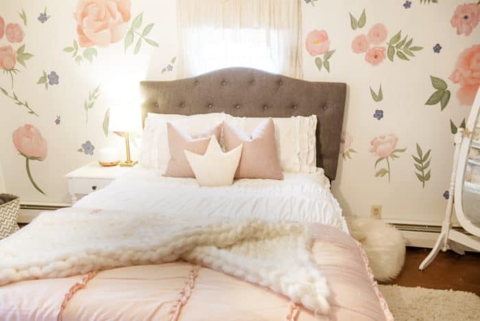 Girls pink bedroom with flowers on wall, and soft bedding in pink and white.