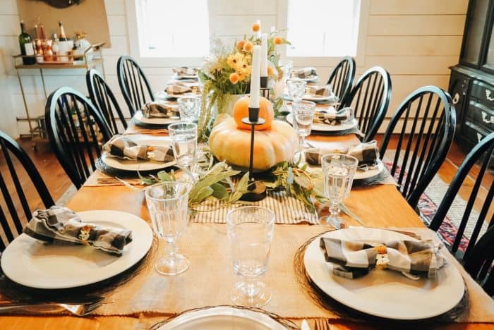Thanksgiving table with pumpkins, burlap runner, and buffalo checked napkins.