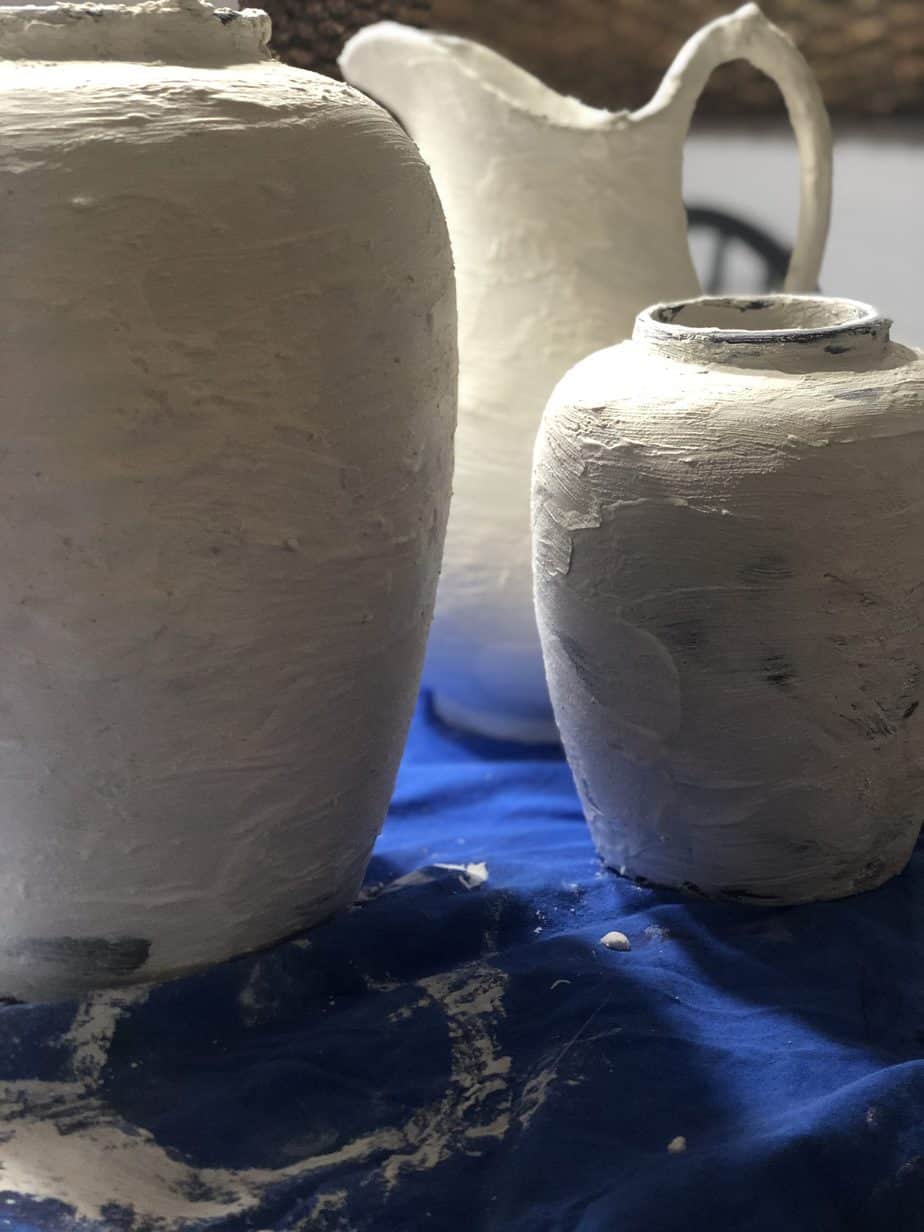 Vases covered in plaster on a blue drop sheet.