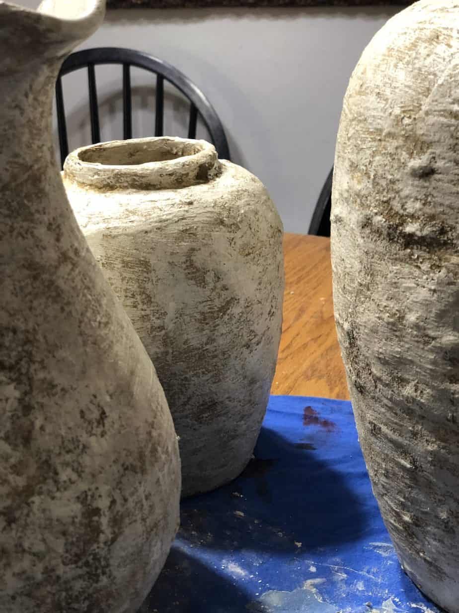 Vase covered in mud mixture outside drying.
