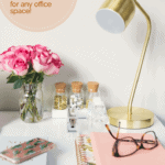 glasses on a desk with gold lamp and pink flowers