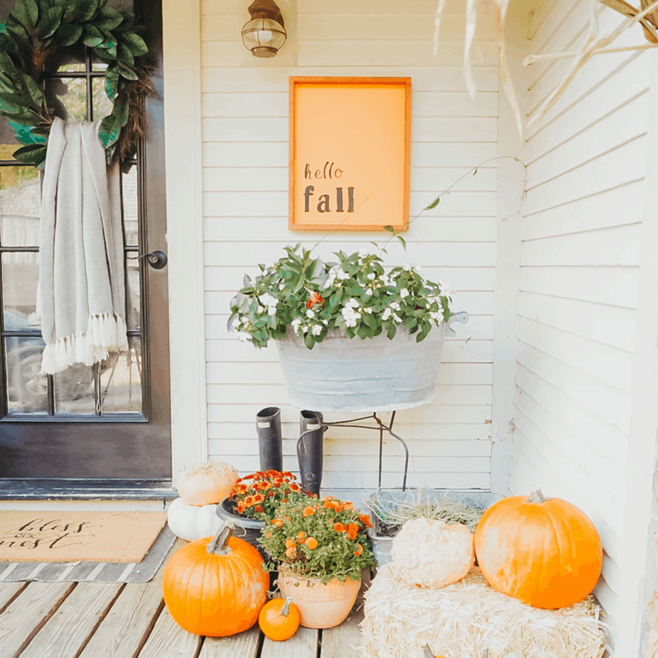 hello fall sign with mums and pumpkin on front porch