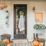 front porch decor with mums, pumpkins, and fall sign