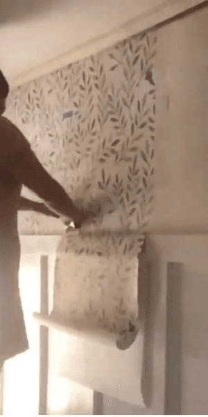 Woman smoothing out wallpaper with tool.