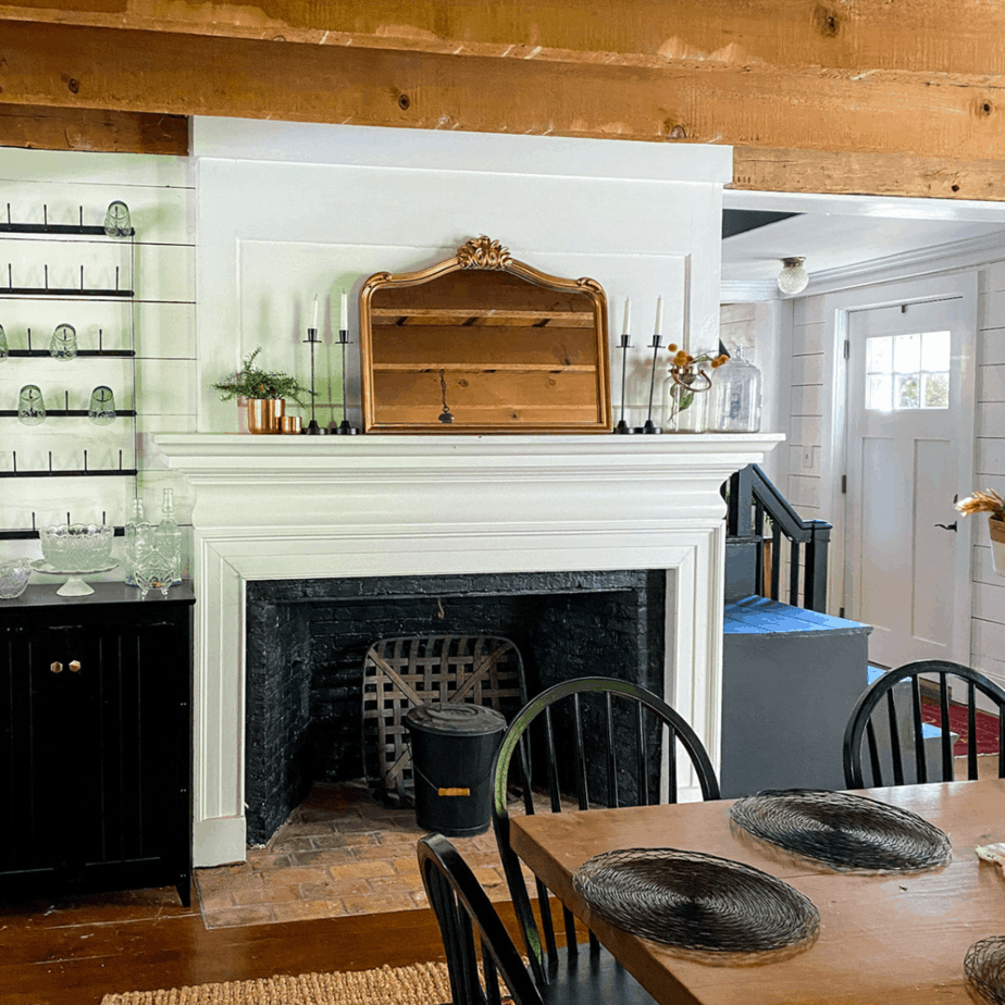 farmhouse fireplace with gold mirror and black candlesticks on mantel