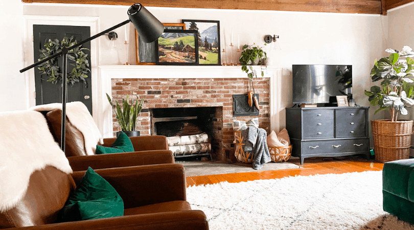 brick fireplace with large farmed landscape art and a plant