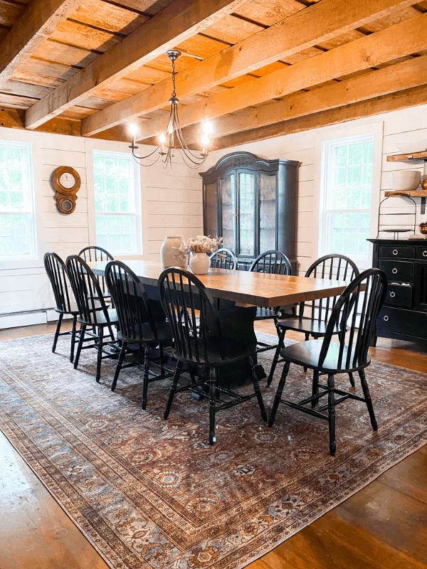 Farmhouse style dining room with black chairs, exposed beams, and shiplap on walls.