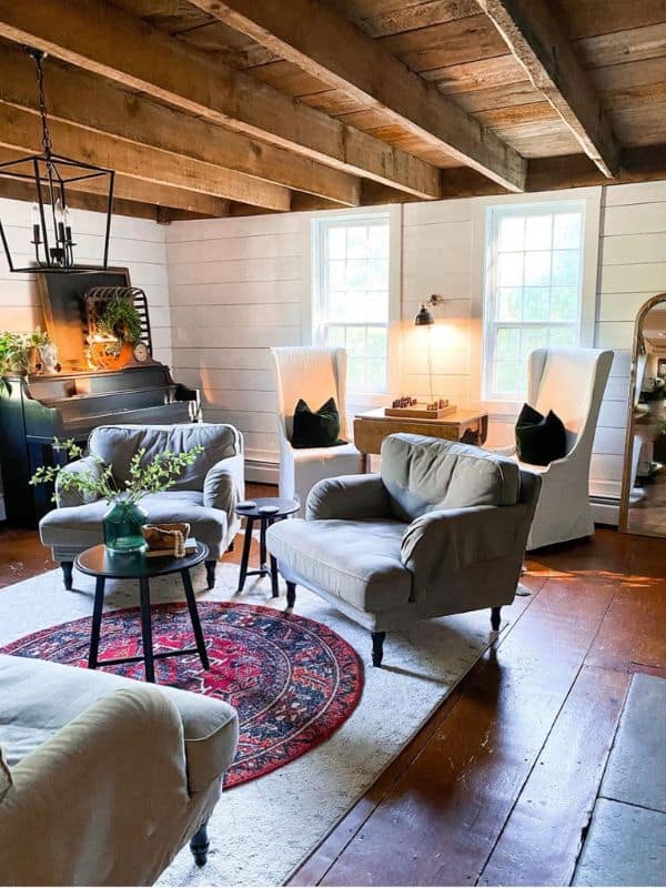 living room with white shiplap walls and trim and Woden beams on ceiling.