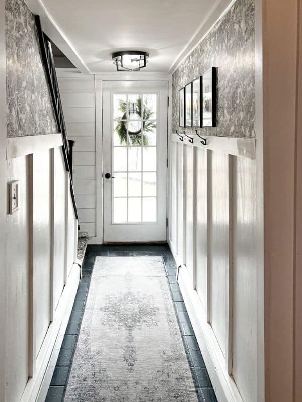 Entryway with black painted tiles and a gray rug.