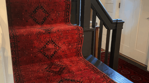 Red rug with binder edges on a black staircase.
