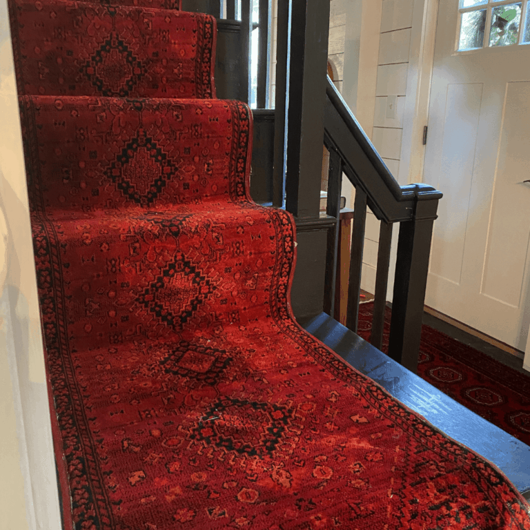 Red rug with binder edges on a black staircase.
