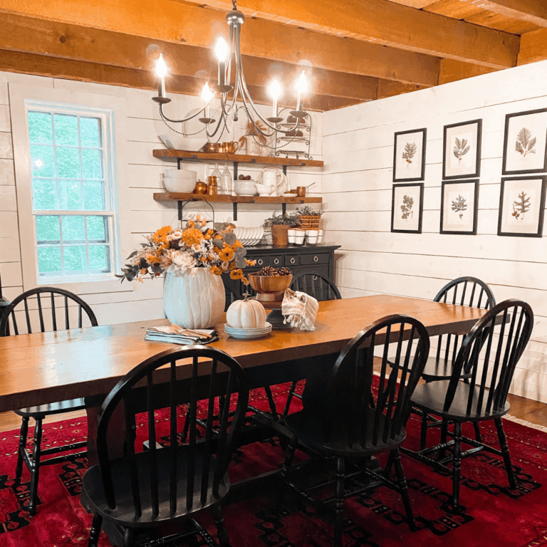 dining room decorated for Fall with. red rug, wooden table, and black chairs.