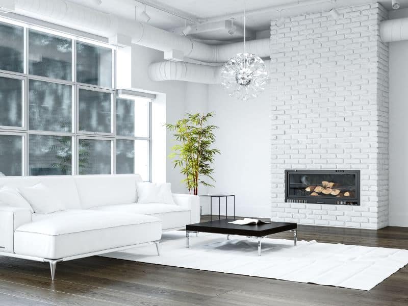 All white living room with a tall whitewashed brick fireplace.