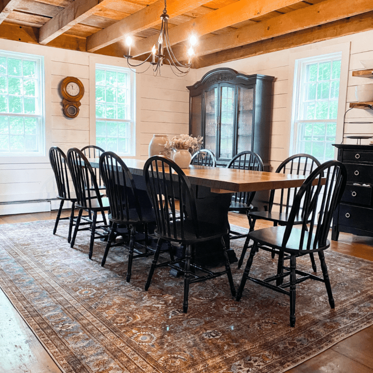 Farmhouse dining room with a large wooden table and black farmhouse chairs.