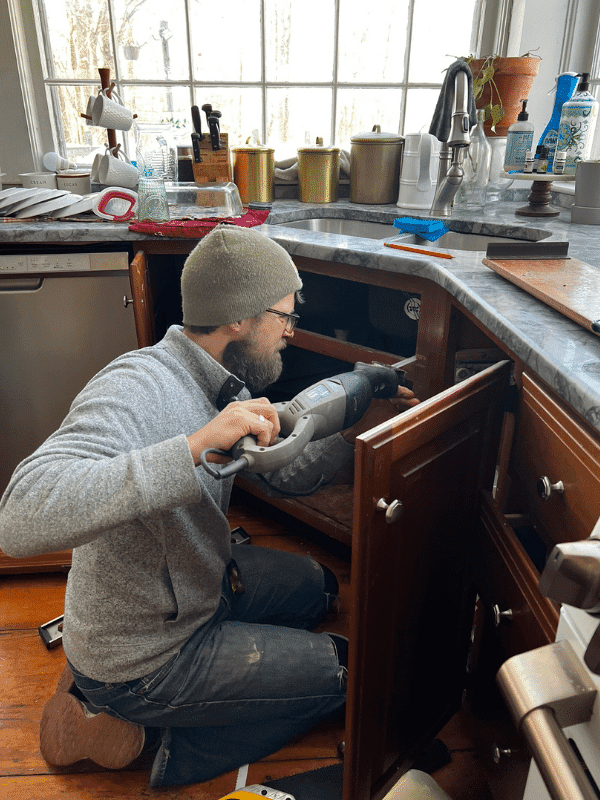 Man cutting cabinet to widen the front to fit the farmer sink.