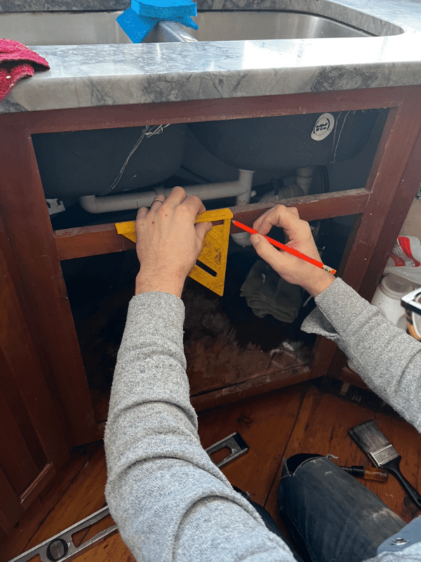 Man measuring center of the sink cabinet to cut for retrofit cabinet.