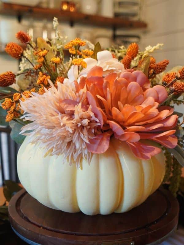 small pumpkin vase with faux flowers.
