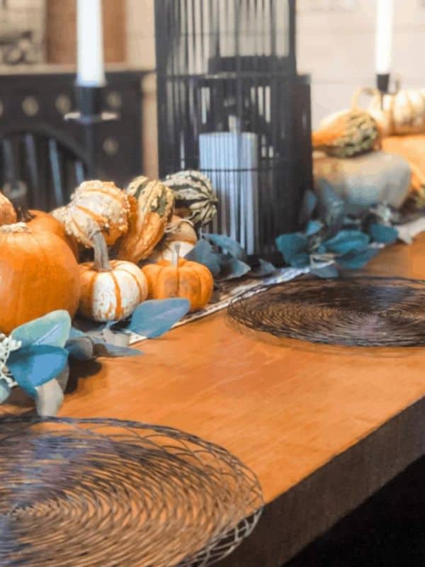Dining table with pumpkin, gourds, and lanterns.