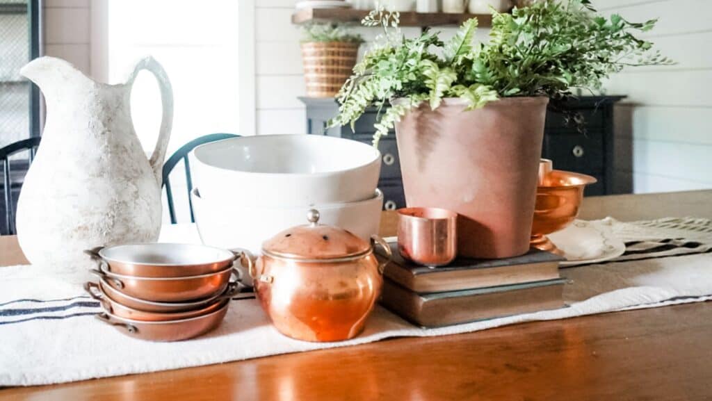 Copper cups and jars as centerpiece on dinging table.
